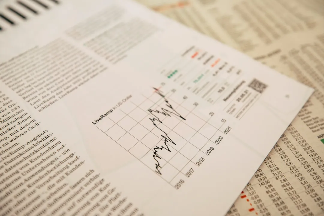 株価の推移グラフが載った経済紙の紙面。隣のページには数字の一覧が並んでいる。