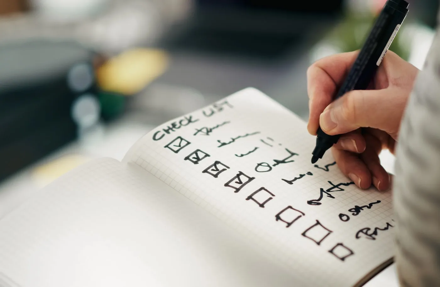方眼ノートに「CHECK LIST」と書き、チェックボックス付きの項目にペンで印を入れているところ。