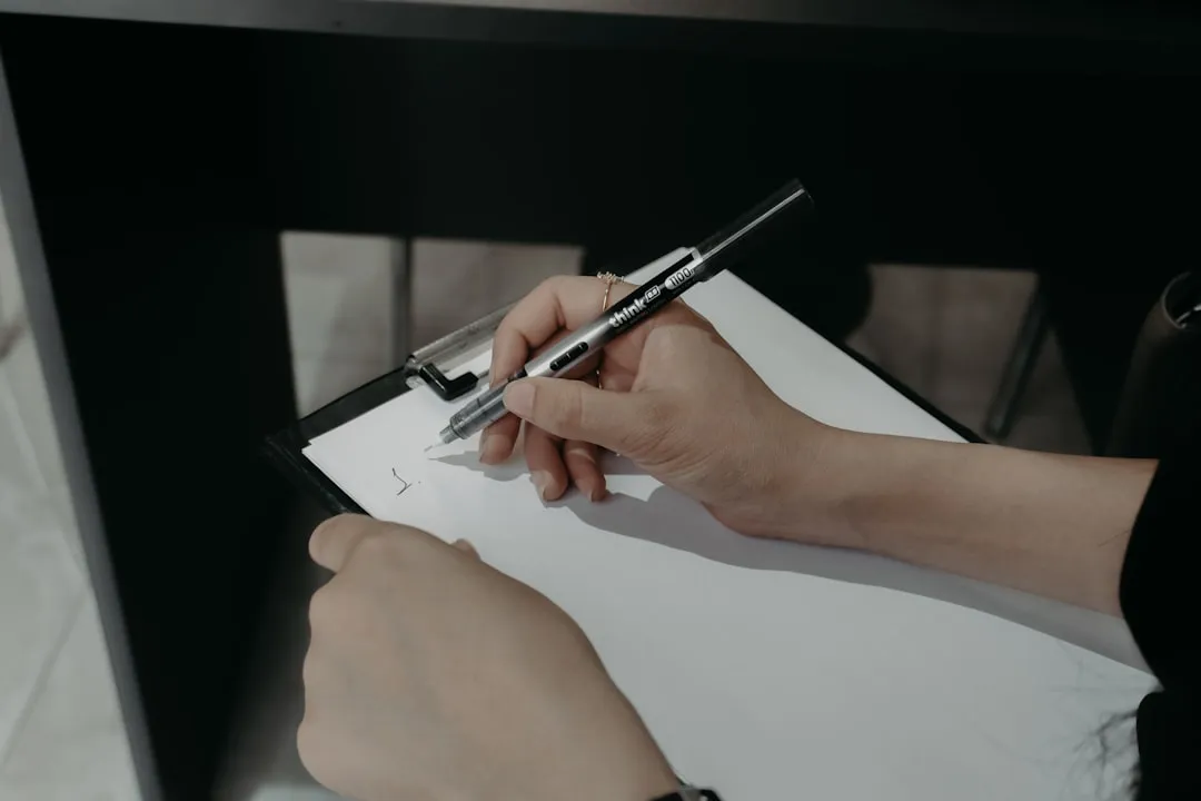 クリップボードに挟んだ白紙に、ペンで書き込もうとしている手元。